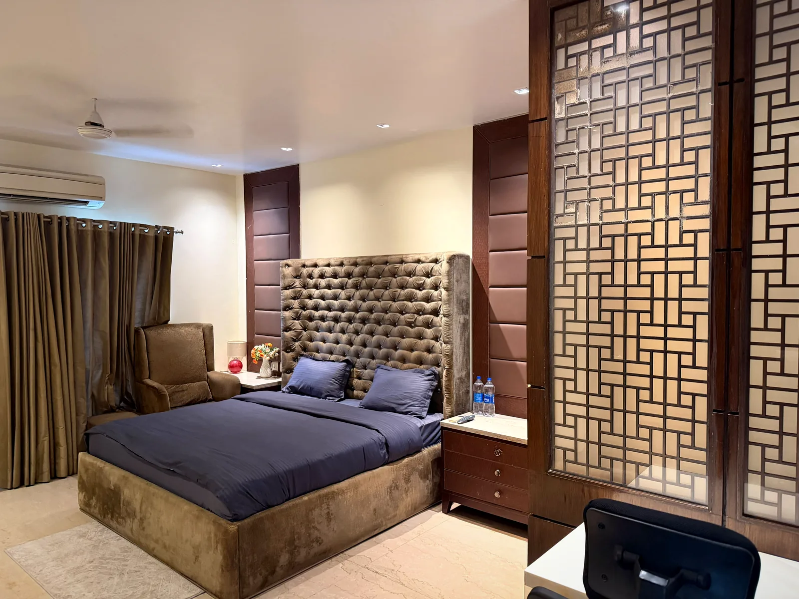 Bedroom with tall tufted headboard and lattice screen divider at Nivasa Villas, Gurgaon