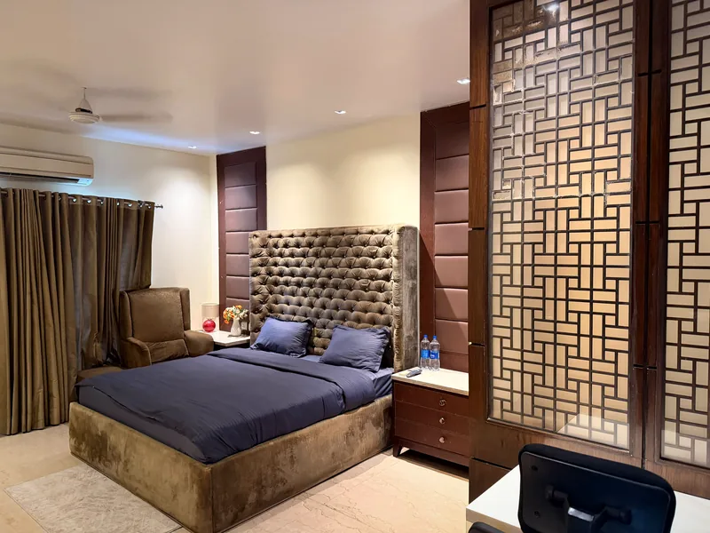 Bedroom with tall tufted headboard and lattice screen divider at Nivasa Villas, Gurgaon