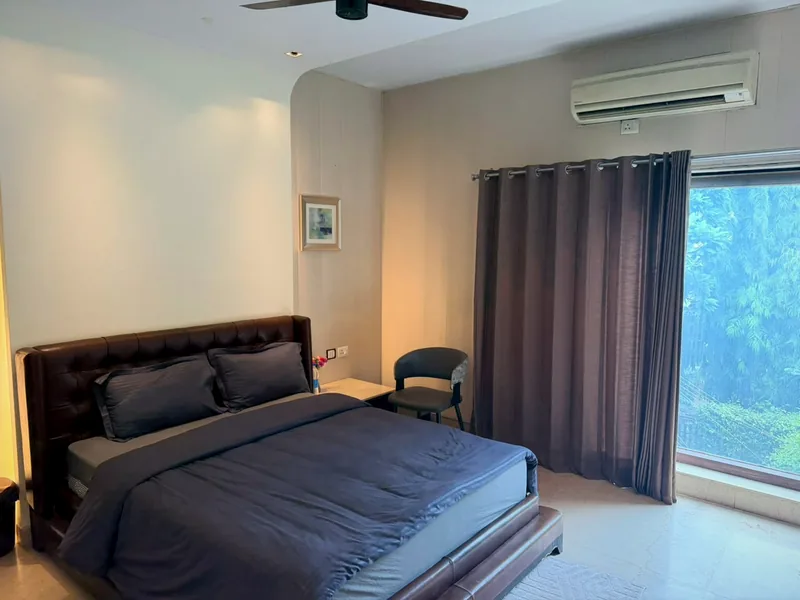 Bedroom with garden-view window at Nivasa Villas, DLF Phase 3, Gurugram