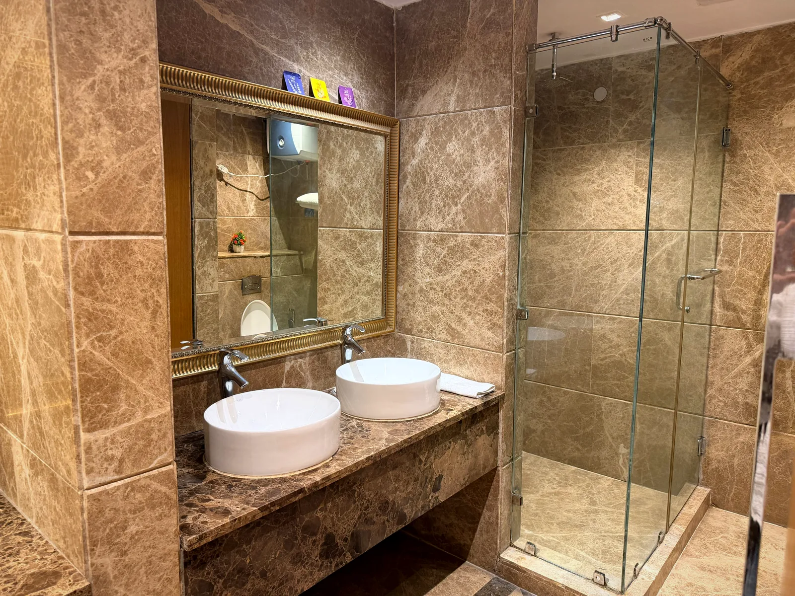 Marble bathroom with twin vessel basins and glass shower at Nivasa Villas, Gurugram